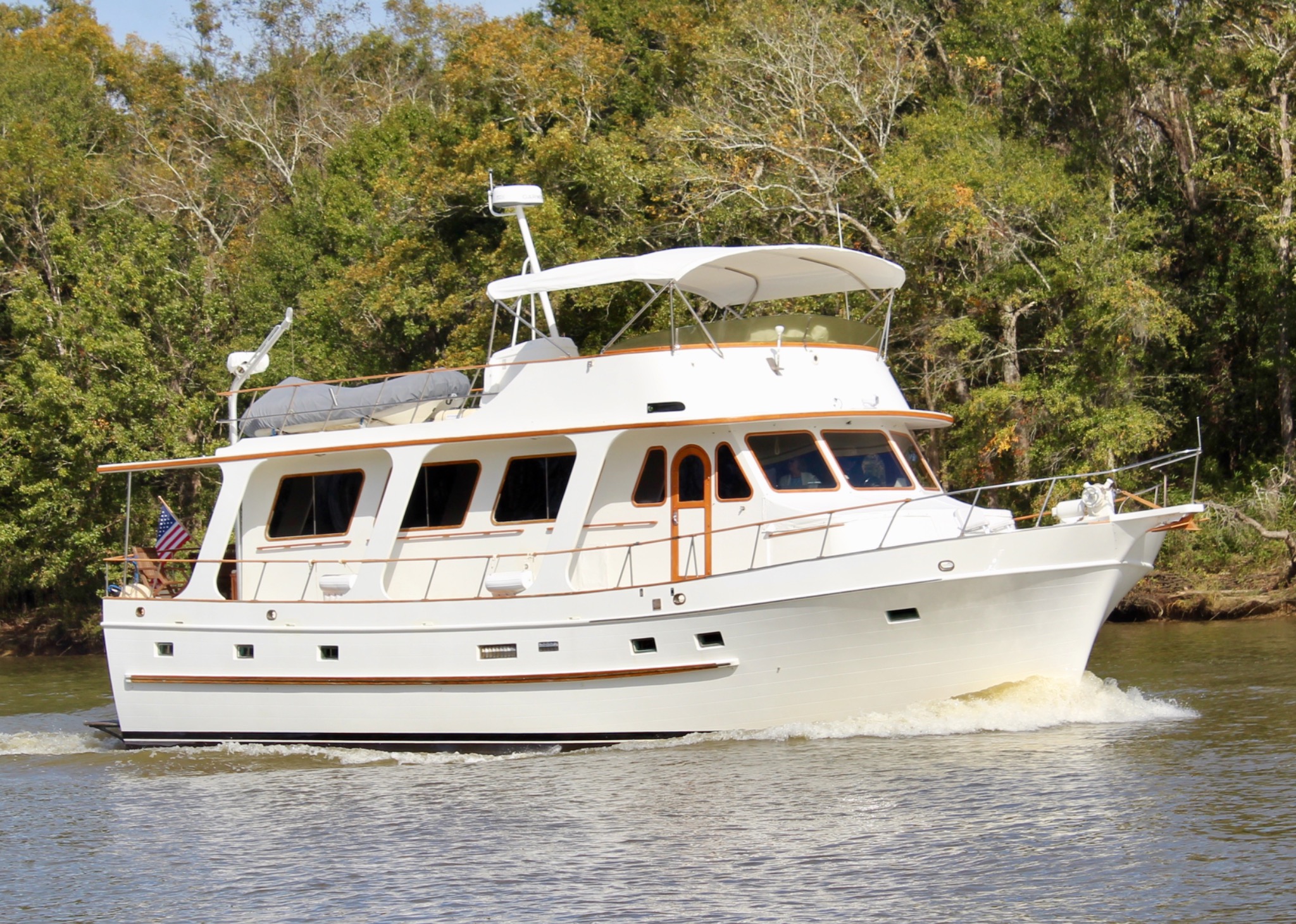 Hunky Dory, a white classic trawler, underway on a wooded river